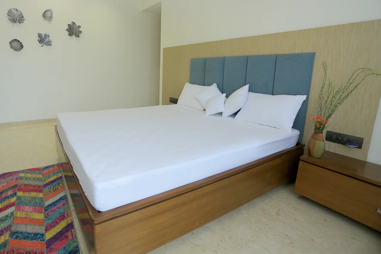 White fitted bedding on a bed with a blue upholstered headboard